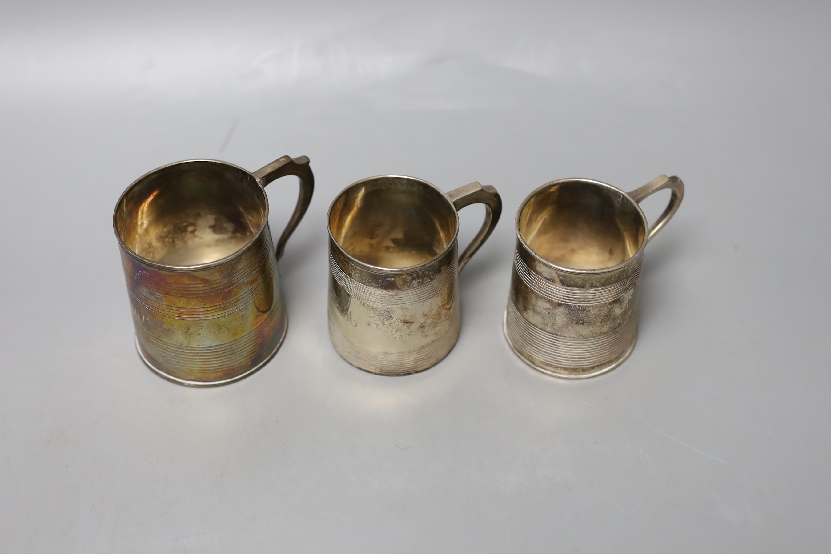 Three small Georgian silver mugs, two with two reeded bands, Stephen Adams I, London, 1801, 64mm and makers mark rubbed, London, 1808 (with later engraved inscription to the base) and one with three reeded bands, London,